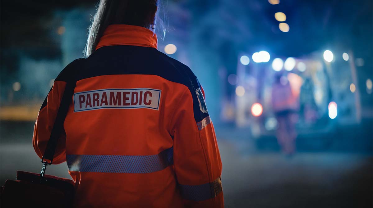 a paramedic carries her pack toward an ambulance