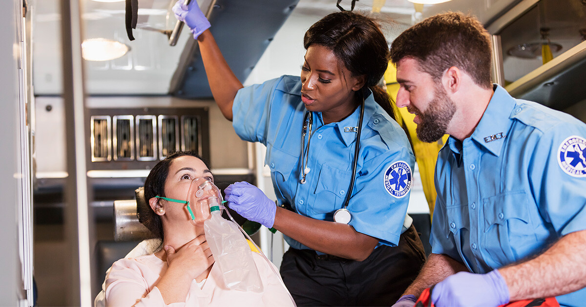 two paramedics care for a patient inside an ambulance