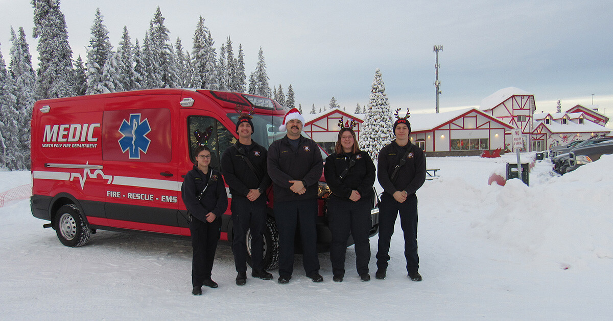 north pole fire department crew stands in front of truck