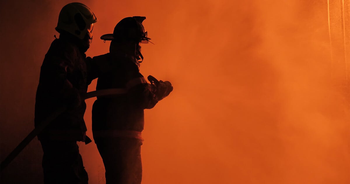 Firefighters surrounded by smoke.